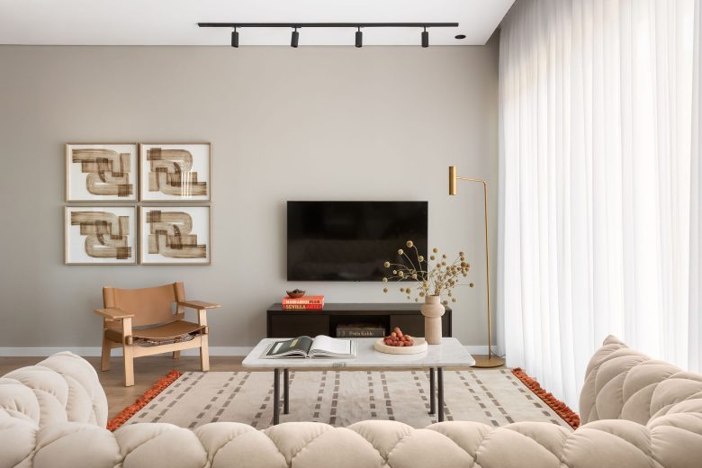 Elegant modern living room in White City Limassol Aparthotel, featuring a plush beige sectional sofa, chic leather armchair, and abstract art on a neutral wall.