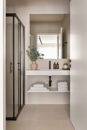 Elegant modern bathroom in White City Limassol Aparthotel featuring a glass shower, floating vanity, and tastefully chosen accessories.