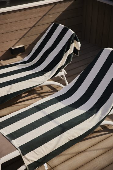 Two striped lounge chairs with towels on the rooftop deck at White City Limassol Hotel.